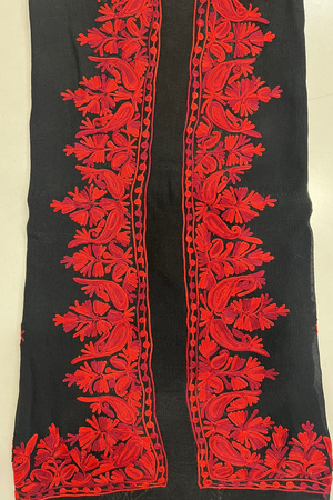 Black fabric with red floral embroidery on a beige background