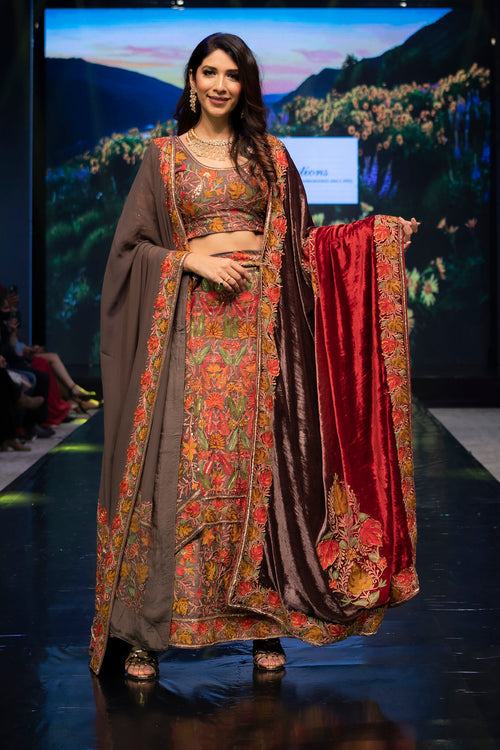 Model wearing a traditional outfit with a floral design on a runway.