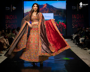 Model walking on a runway in a traditional outfit at the India Designer Show event.