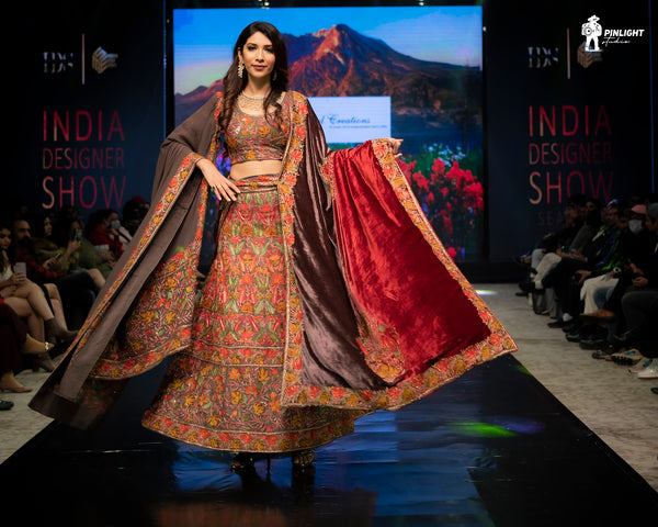 Model walking on a runway in a traditional outfit at the India Designer Show event.