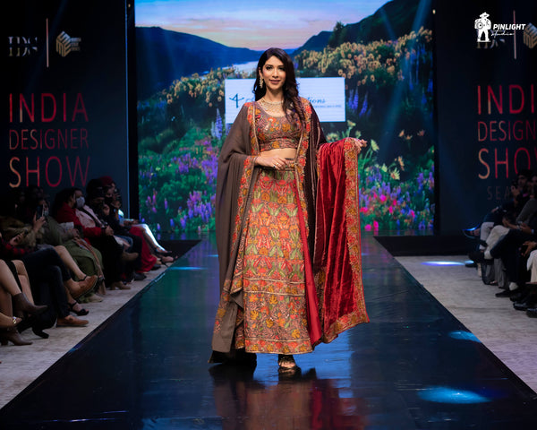 Model walking on a runway in a traditional outfit at the India Designer Show event.
