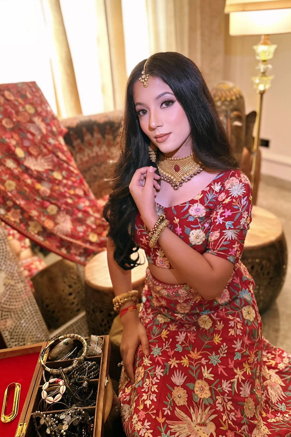 Woman in a red floral dress with jewelry in an indoor setting