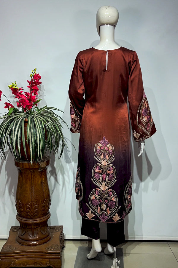 #OmbreWine&Purple Mannequin wearing a rust-colored dress with floral patterns next to a decorative plant on a white background