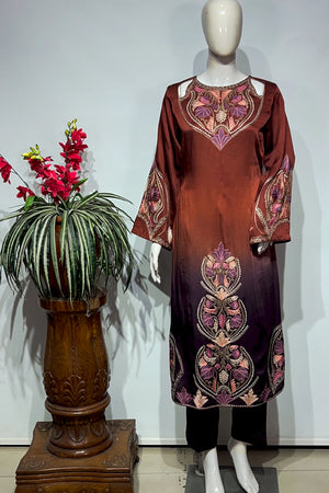 #OmbreWine&Purple Mannequin wearing a brown dress with floral patterns next to a decorative plant on a wooden stand.