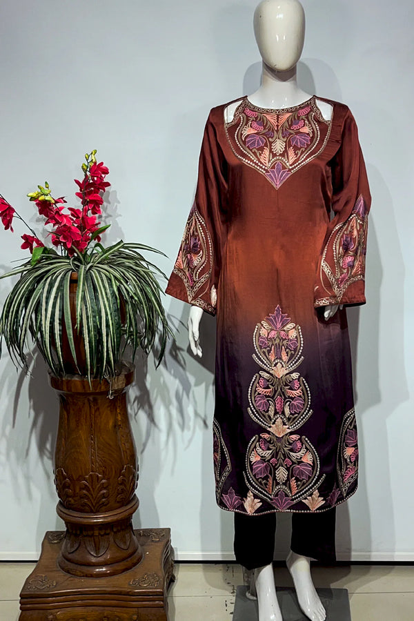 #OmbreWine&Purple Mannequin wearing a brown dress with floral patterns next to a decorative plant on a wooden stand.