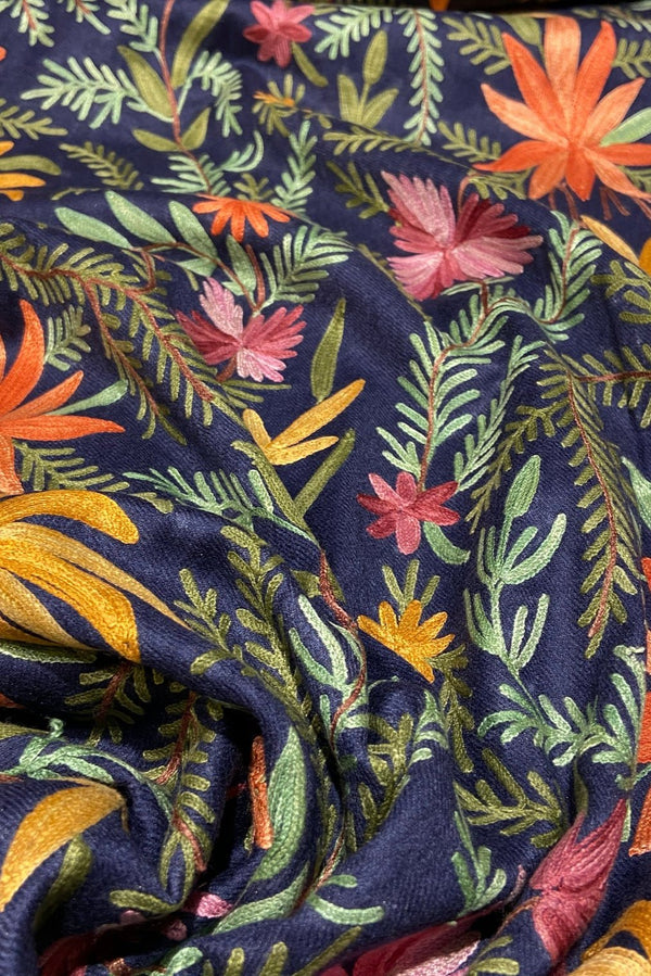 Embroidered fabric with colorful floral and leaf patterns on a dark blue background