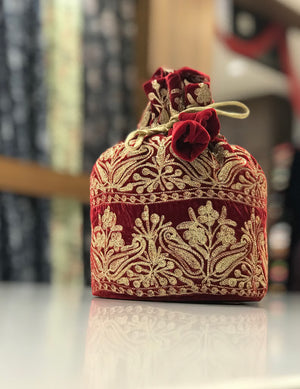 #Red Decorative red and gold embroidered bag on a reflective surface with a blurred background