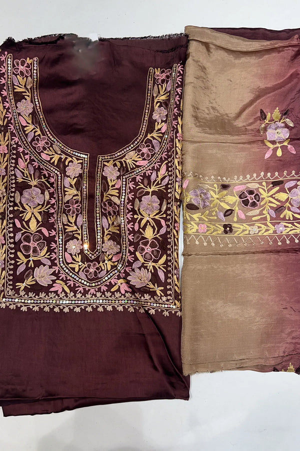 #Wine Two pieces of fabric, one with a floral Aari and sequence work in the center and the other with a border featuring the same style of work.