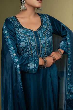 #TealBlue Woman wearing a blue embroidered traditional outfit with a plain background