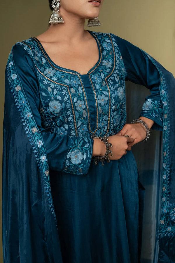#TealBlue Woman wearing a blue embroidered traditional outfit with a plain background