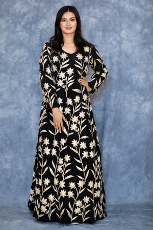 Woman wearing a black dress with white floral patterns against a blue background