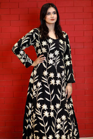 Woman wearing a black floral dress against a red brick wall