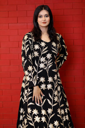 Woman wearing a black floral dress against a red brick wall
