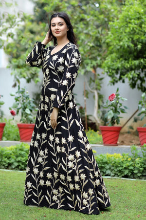 Woman wearing a black floral dress standing in a garden.