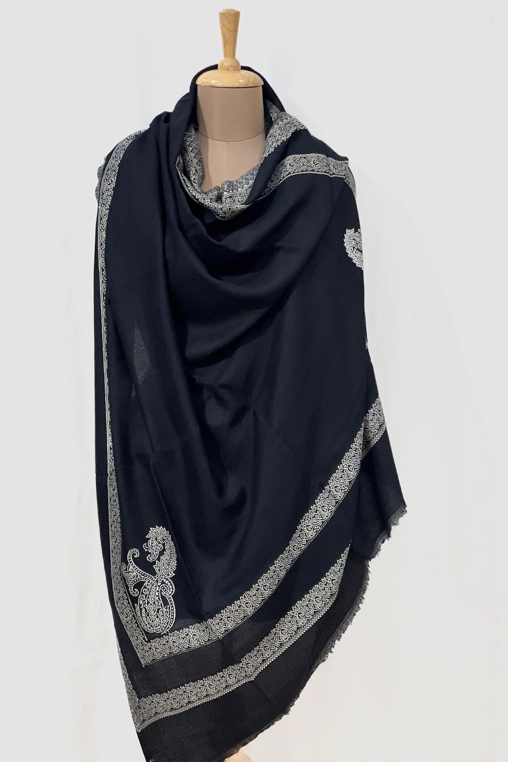 #Black - Black wool shawl with ivory woven paisley border draped over a mannequin, showing drape volume and corner boteh detail