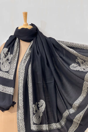 #Black - Black wool shawl draped around the neck and belted at the waist on a mannequin, front-facing view highlighting the central ivory border stripe and corner paisleys