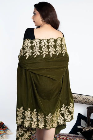 #OliveGreen Woman wearing a green cape with white floral embroidery on a white background