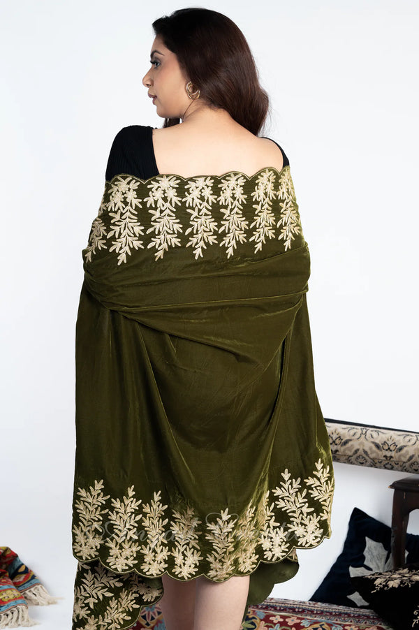 #OliveGreen Woman wearing a green cape with white floral embroidery on a white background