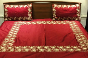 #Maroon Red bedspread with gold embroidery on a wooden bed