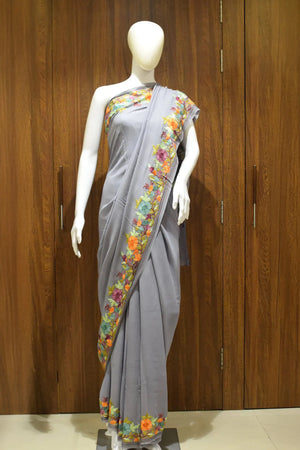 #Gray saree with floral patterns on a mannequin against a wooden background