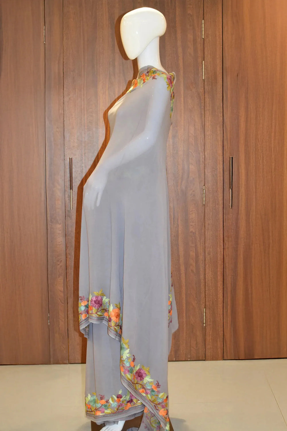 #Gray saree with floral patterns on a mannequin against a wooden background