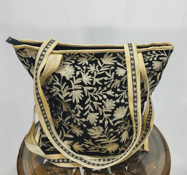 Black floral embroidered bag with gold trim on a white background