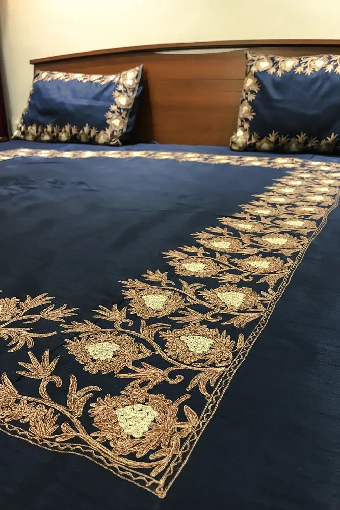 #Navyblue bedspread with gold embroidery on a bed with matching pillows.