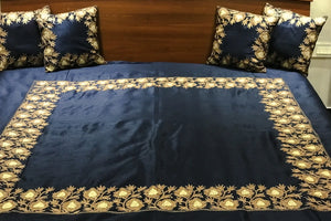 #Navyblue bedspread with gold embroidery on a bed with matching pillows.