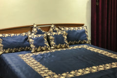 #Navyblue Bed with blue floral bedding and pillows against a white wall.