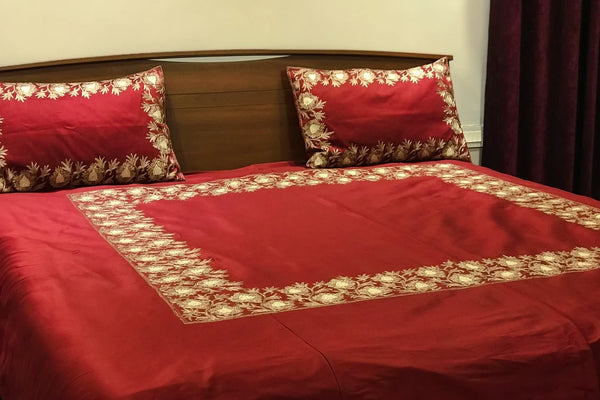 #Maroon Red bedspread with floral patterns on a wooden bed frame.