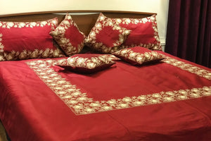 #Maroon Red floral patterned bedspread and pillows on a bed.