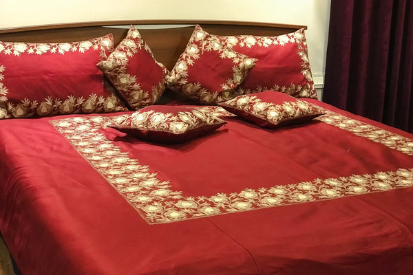 #Maroon Red floral patterned bedspread and pillows on a bed.
