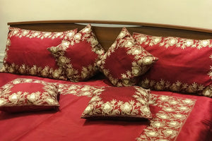 #Maroon Red bedspread with floral patterns on a wooden headboard