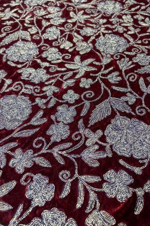 Close-up of a fabric with copper floral embroidery on a maroon background