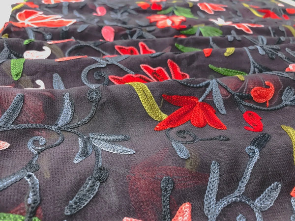 Embroidered fabric with red flowers and green leaves on a dark background