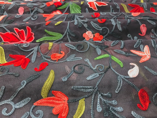 Embroidered fabric with colorful floral patterns on a dark background