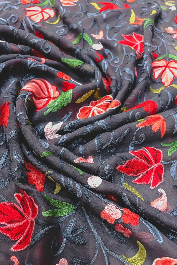 Embroidered fabric with red flowers and green leaves on a dark background
