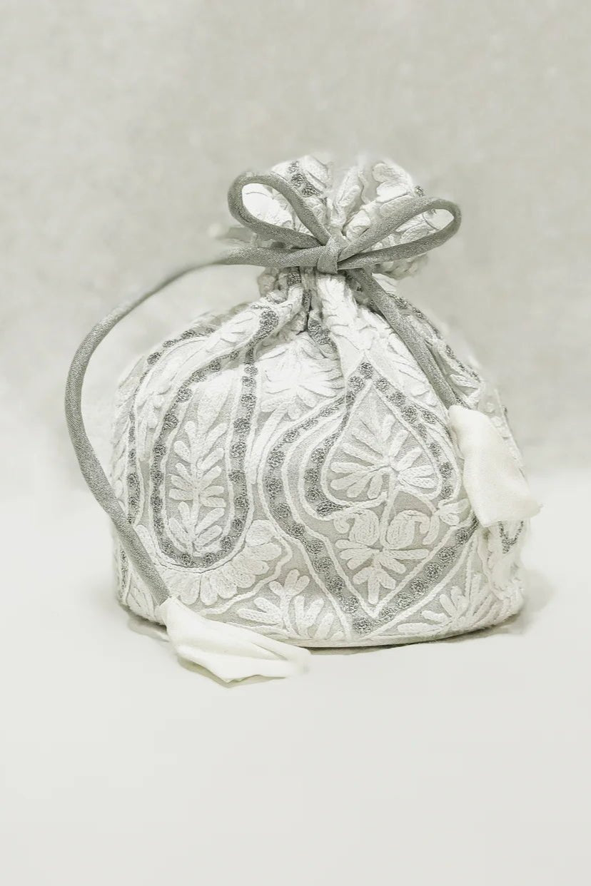 White fabric bag with silver embroidery on a light gray background