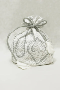 White fabric bag with silver embroidery on a light gray background