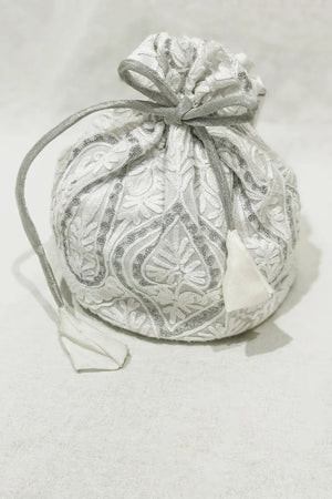 Silver drawstring bag with intricate patterns on a light gray background