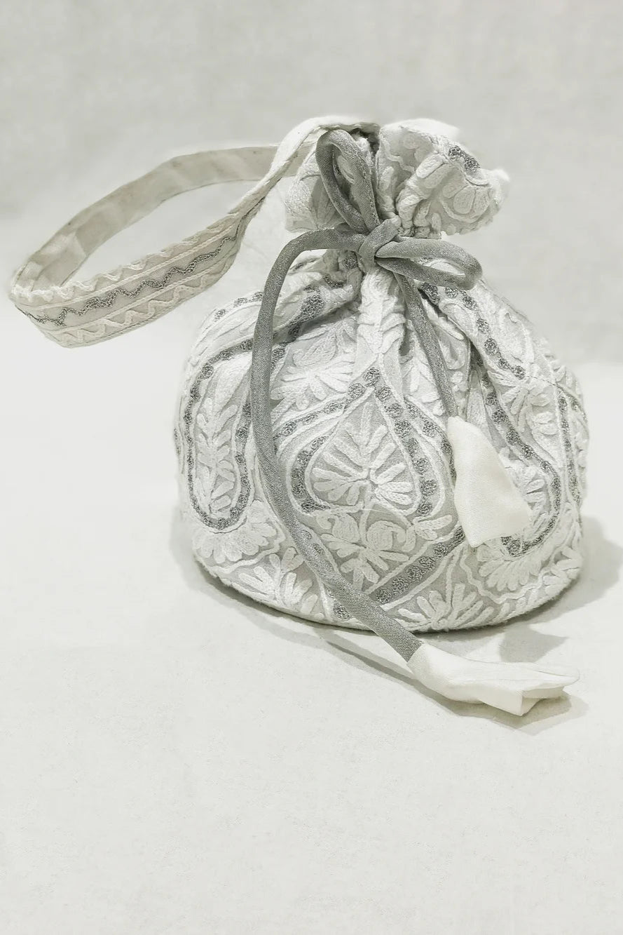 White fabric bag with silver embroidery on a light gray background
