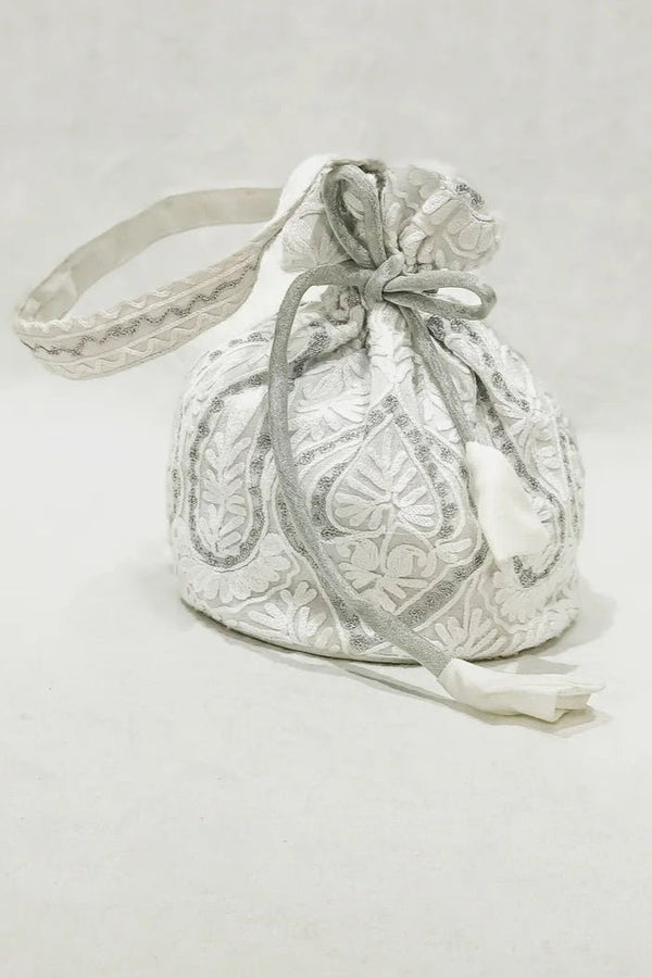 White drawstring bag with intricate patterns on a light gray background