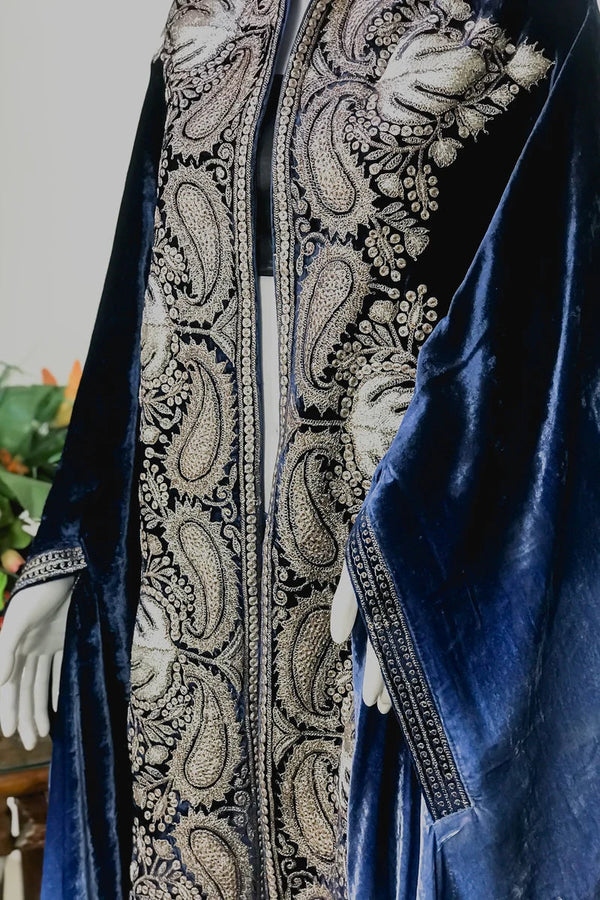 Blue velvet garment with intricate white embroidery on a neutral background