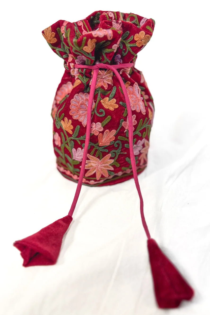 Red fabric drawstring bag with floral embroidery on a white background