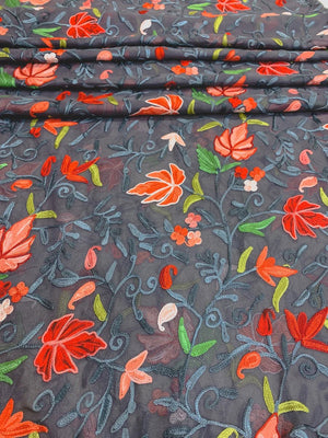Embroidered fabric with red and green floral patterns on a dark background