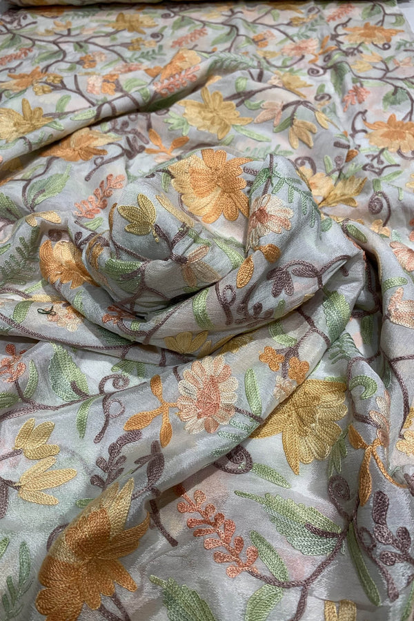 Floral fabric with orange, green, and brown colors on a light background