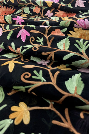 Close-up of embroidered fabric with colorful floral patterns on a black background
