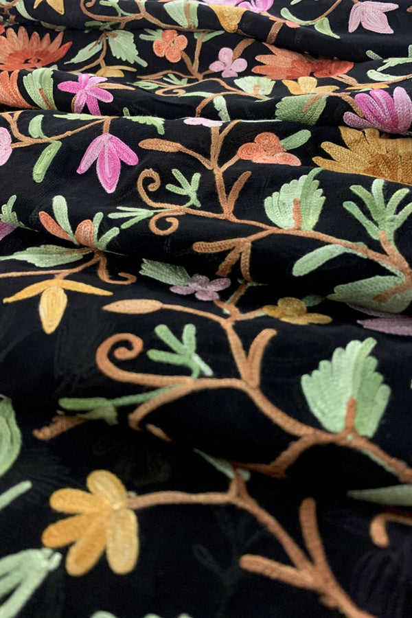 Close-up of embroidered fabric with colorful floral patterns on a black background