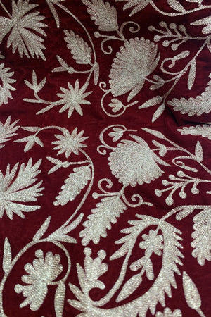 #Red Close-up of maroon fabric with intricate dull gold floral embroidery