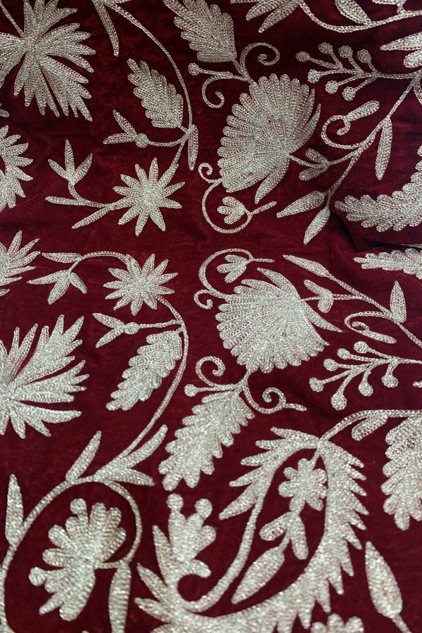 #Red Close-up of maroon fabric with intricate dull gold floral embroidery